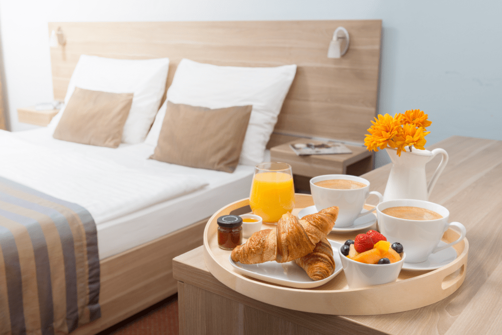 Bed with a tray to the side, has breakfast on it