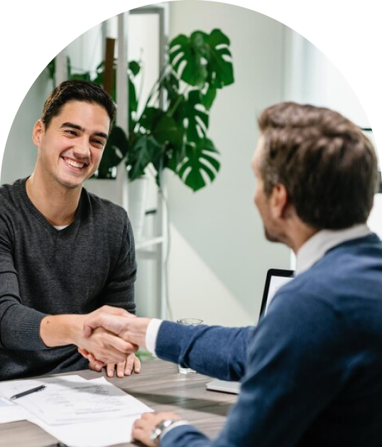 Two men shake hands and smile.