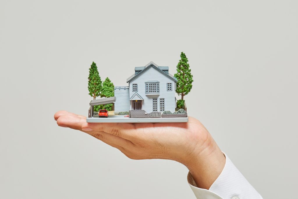 Hand holding a model house representing property owners insurance
