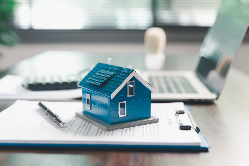 Model house placed on paperwork used to illustrate property insurance